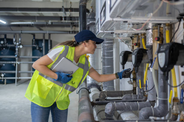 technician checking heating system in the boiler room with tablet in hand